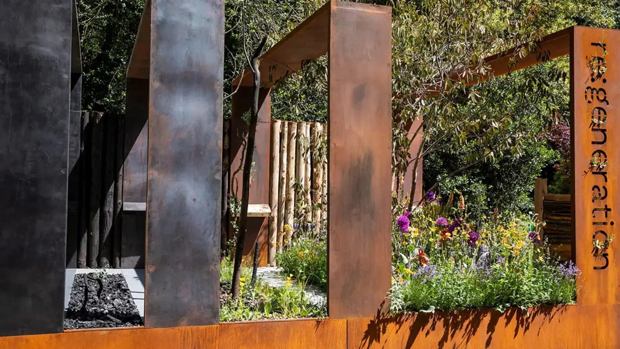 A modern sanctuary garden featuring rusty Corten steel frames, a pale timber log wall, and raised beds with purple and yellow wildflowers.