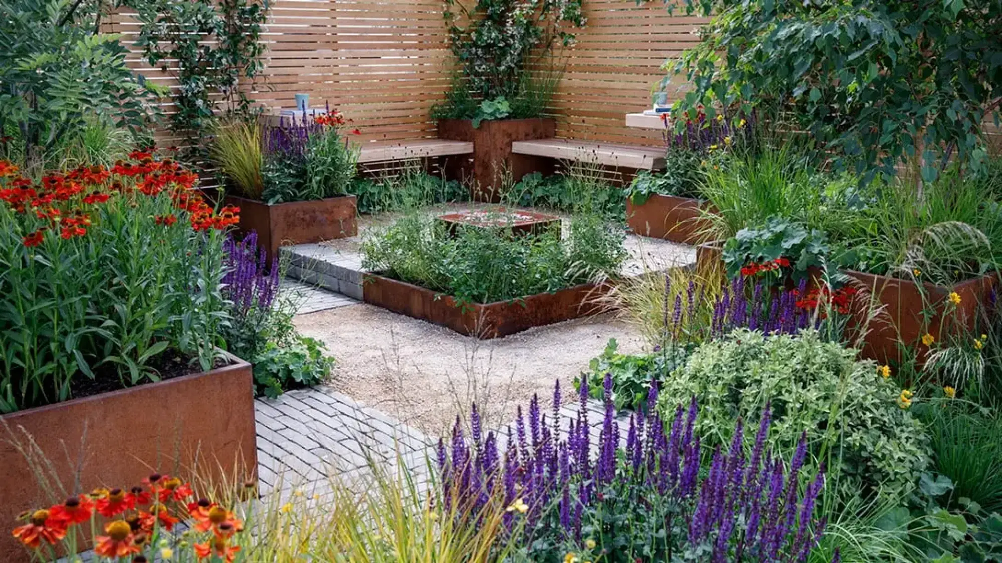 A Get Started Garden features rust planters with vibrant planting, a central fire pit, timber benches, and a slatted screen.